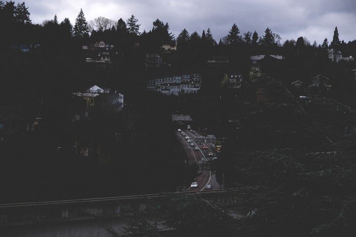 4K traffic on a road through a dark forest town