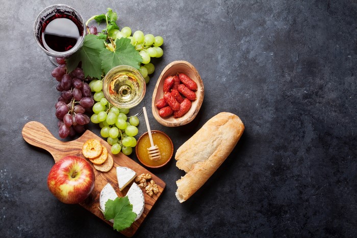 Wine and cheese board with grapes, bread, and sausages