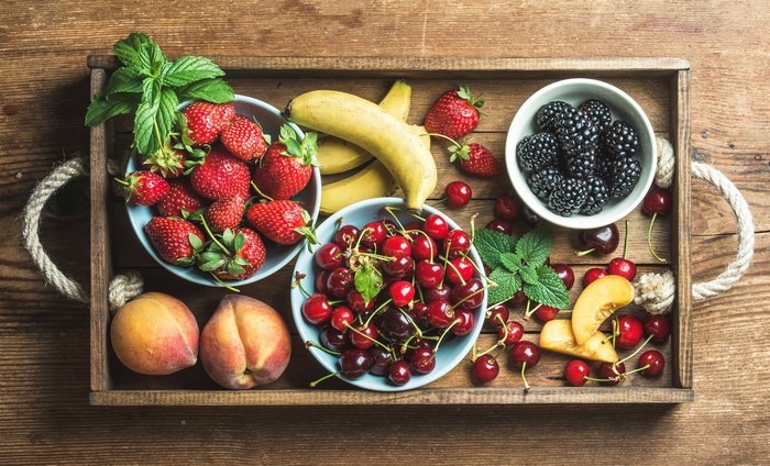 Tray of fresh fruits including strawberries, blackberries, cherries, bananas, and peaches