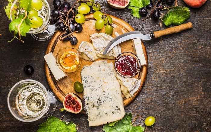 Cheese board with grapes, figs, jam, and wine