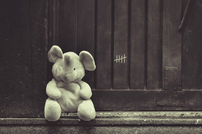 Stuffed elephant sitting by a door with tally marks