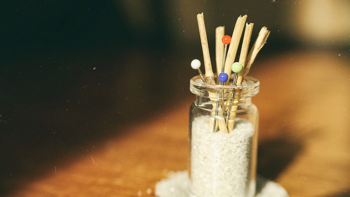 Still life of pins in a jar with wooden sticks
