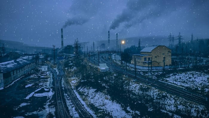 Industrial factory with smoking chimneys in winter snow
