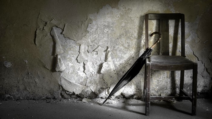 Chair and umbrella against a peeling wall