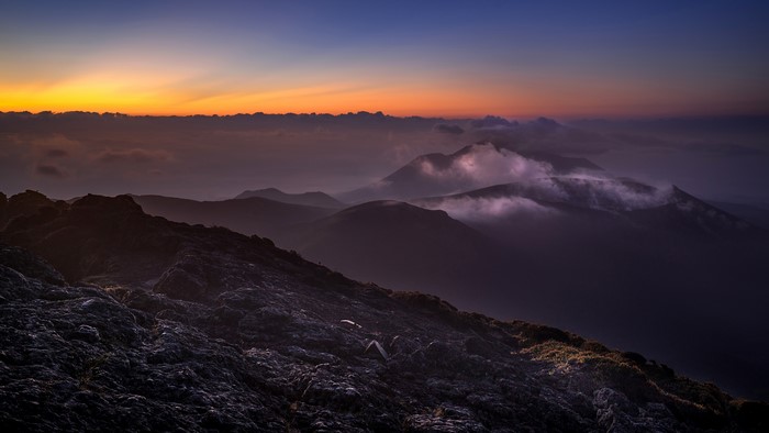 Dark mountain landscape at sunrise with clouds