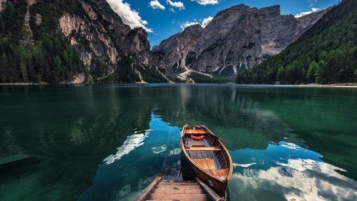 Wooden boat on a clear lake with mountains and forest