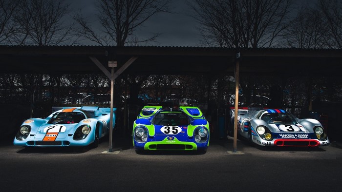 Three vintage Porsche race cars under a canopy