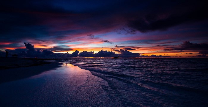 Sunset over the ocean with colorful clouds and waves