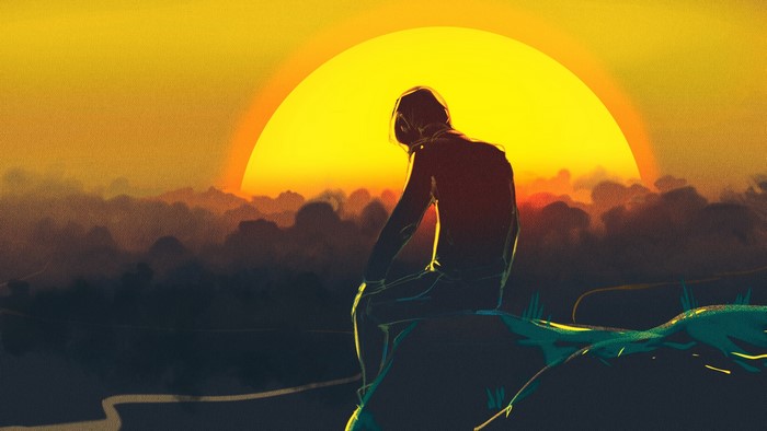 Person sitting on a rock watching the sunset