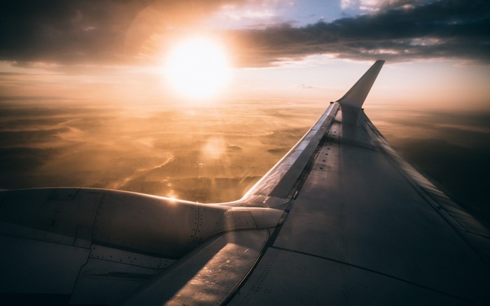 Airplane wing against sunset sky over land