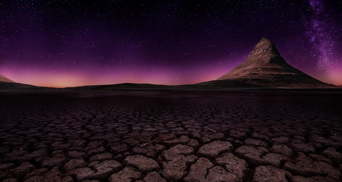 Cracked desert under a starry purple night sky