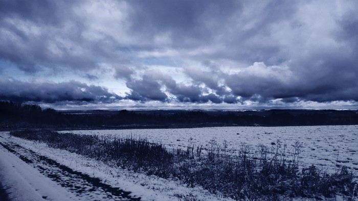 Winter field with snow and dramatic clouds