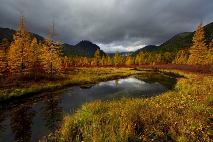 Autumn landscape with river and mountains under clouds