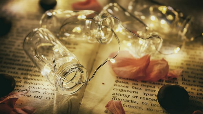Glass bottles with fairy lights on a book