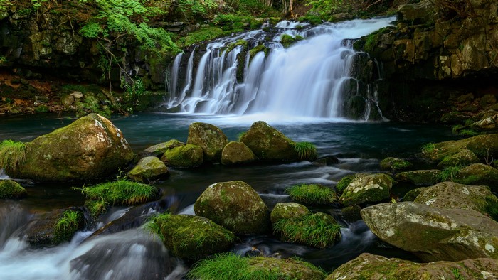 4K waterfall cascading over mossy rocks in nature