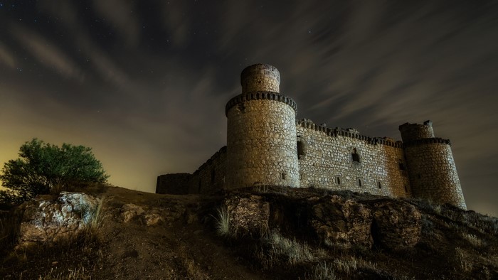 Castle ruins at night under a cloudy sky