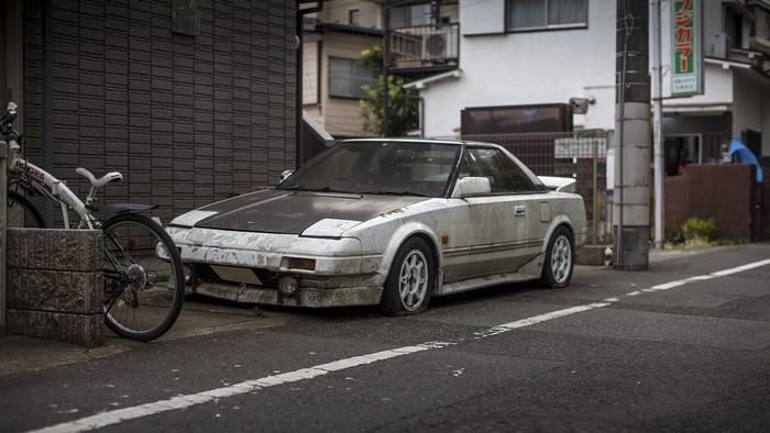 Dirty white Toyota MR2 with pop-up headlights parked on street
