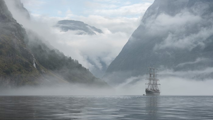 Tall ship sailing through a foggy fjord in Norway