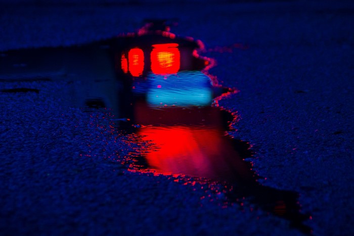 Reflection of red and blue lights in a puddle on asphalt
