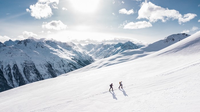 Two hikers ascend a snowy mountain slope
