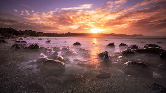 4K sunset over rocky beach with ocean