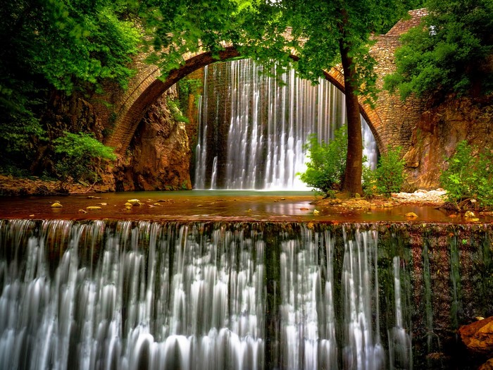Stone bridge over a waterfall in a forest