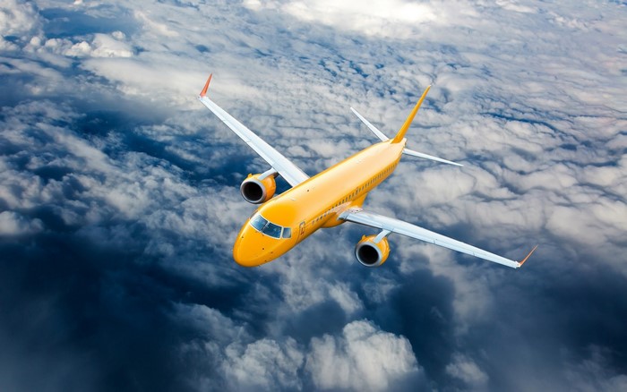 Yellow airplane flying above clouds