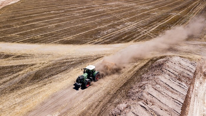 Tractor plowing a dusty field