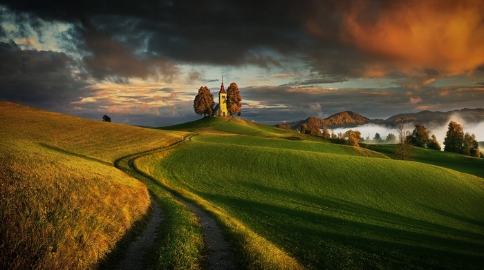 Church on a hill with a path at sunset in Slovenia