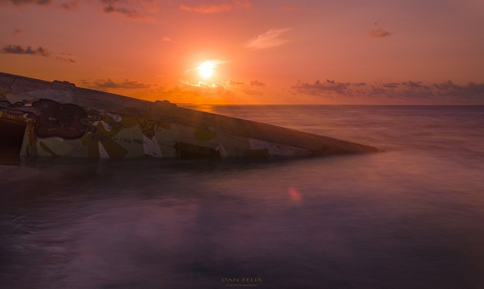 Graffiti covered structure at sunrise over the ocean