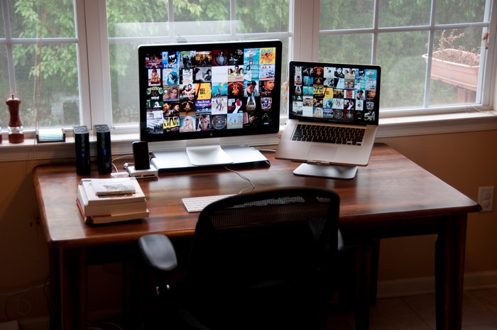 Desk with computers and chair by window
