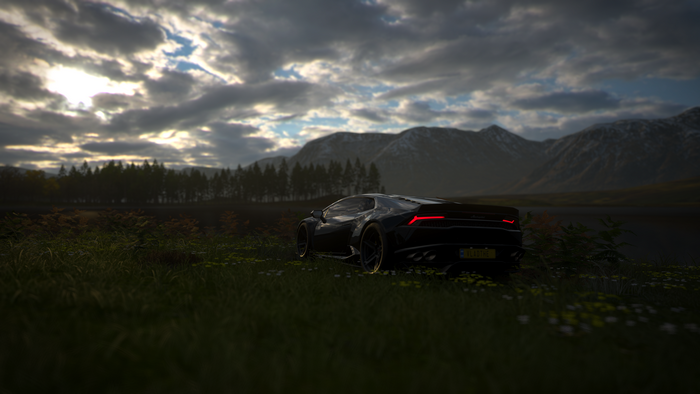 Black Lamborghini in a field with mountains