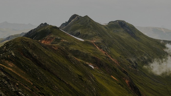 Green mountains shrouded in mist under a cloudy sky
