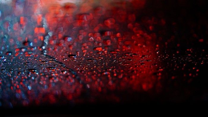Water drops on dark surface with red bokeh lights