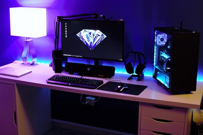 Gaming desk setup with computer, monitor, and lamp