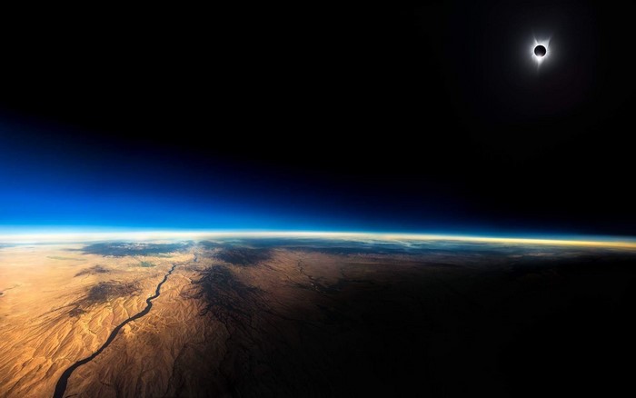 Solar Eclipse Over Earth's Atmosphere and Desert Landscape