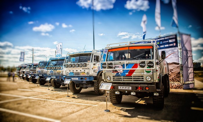 Kamaz rally trucks lined up under a cloudy sky