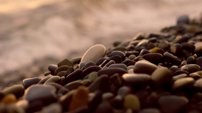 Close-up of wet pebbles on a beach with blurred ocean waves