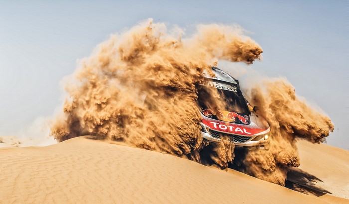 Peugeot rally car driving through desert sand