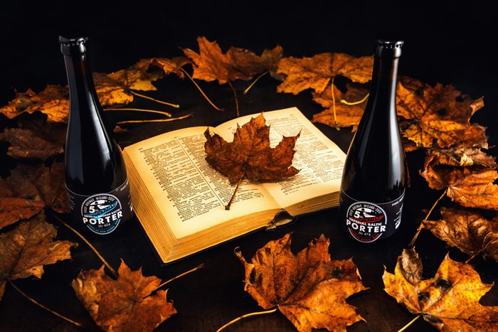 Two bottles of Imperial Baltic Porter surrounded by autumn leaves and an open book