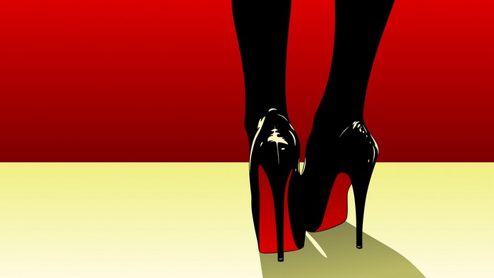Black high heels with red soles on yellow and red background