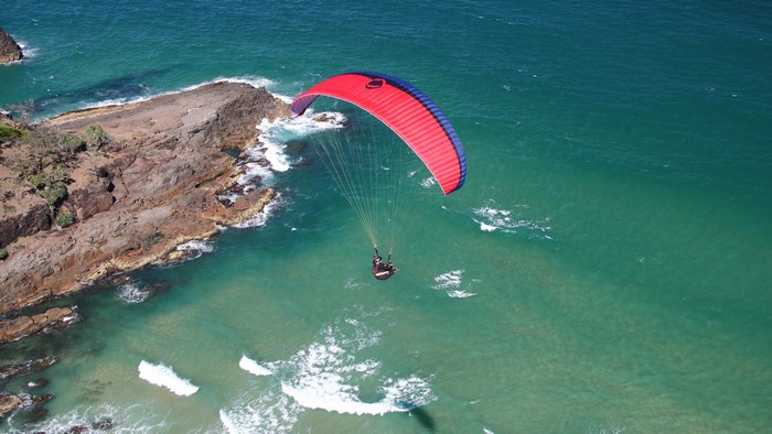 Paragliding over rocky coast and turquoise sea