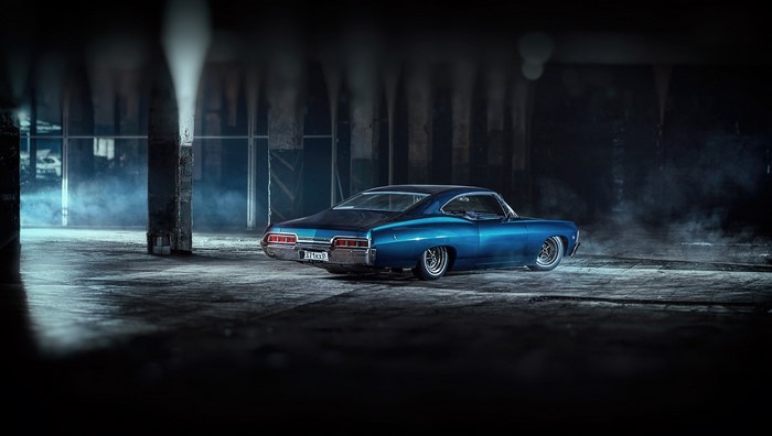 Blue Chevrolet Impala in a dark, smoky garage