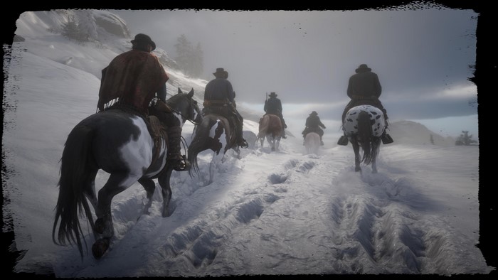 Cowboys riding horses through a snowy landscape in Red Dead Redemption 2