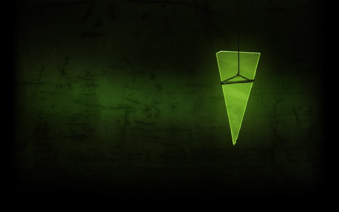 Green triangular object hanging in dark room