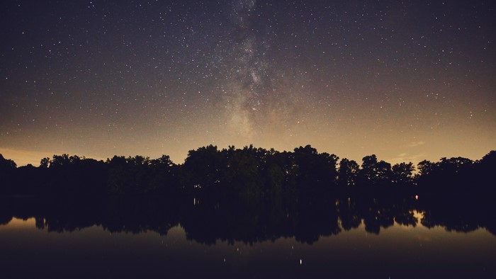 4K Milky Way over a lake and trees