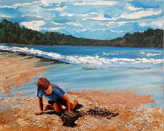 Child playing on a sandy beach with ocean and forest background