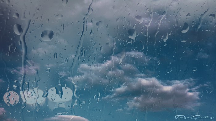 Water drops on glass with clouds in the background