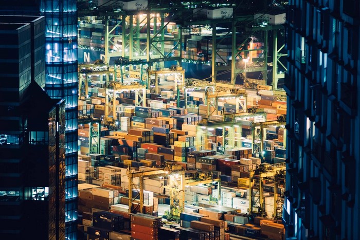 Singapore container port at night with cranes and skyscrapers