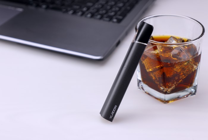 Vladdin vaping device next to a glass of cola